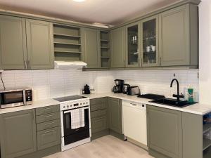 a kitchen with green cabinets and white appliances at Ålesund City Center - Modern 80-m2 flat with 3 bedrooms in Ålesund