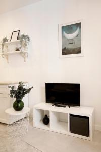 Cozy Studio perfect for couples, Cracow Old Town في كراكوف: غرفة معيشة بيضاء مع تلفزيون بشاشة مسطحة
