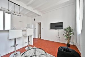 a living room with white walls and a flat screen tv at Au Roi RENE - AC CLIM - WIFI in Avignon