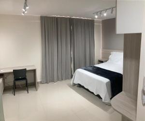 a hotel room with a bed and a desk and a desk at Flat Noroeste Square by CentoEdez in Brasilia