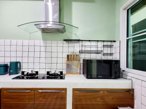 a kitchen with a stove and a microwave at Nimman home 4 bedroom near One Nimman in Chiang Mai