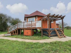 a wooden house with a deck and a slide at Dragonfly Retreat in Pentney