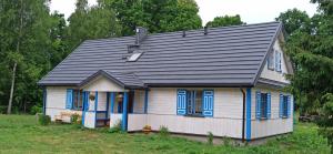 een klein huis met blauwe ramen en een zwart dak bij Gościniec Pod Dębami I 