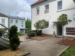 ein weißes Haus mit zwei Bäumen davor in der Unterkunft Wohlfühl Erdgeschoss in Saarbrücken