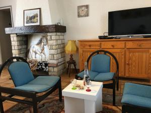 a living room with two chairs and a fireplace at La maison de rolland in Saint-Martin-lʼArs