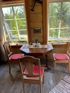 a wooden table and chairs in a room with two windows at Gamlehuset 