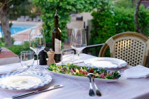 a table with a plate of salad and a bottle of wine at La Ferme D'Augustin in Saint-Tropez