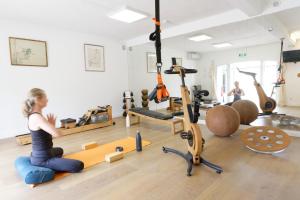 a woman sitting on a pilates reformer in a gym at La Ferme D'Augustin in Saint-Tropez