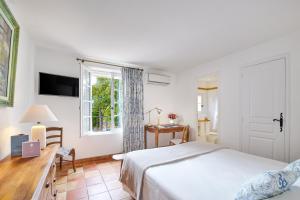 um quarto com uma cama, uma secretária e uma janela em La Ferme D'Augustin em Saint-Tropez