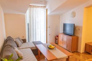 a living room with a couch and a tv at Apartment Sun in Baška Voda