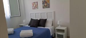 sypialnia z łóżkiem z niebieskim kocem i poduszkami w obiekcie Endless Summer w mieście Fontane Bianche