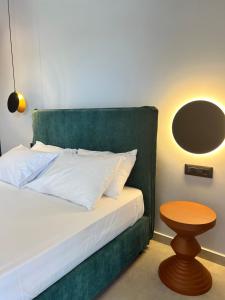 uma cama com uma cabeceira verde ao lado de uma mesa em Cora May Central Villa with private pool 200m to the beach em Faliraki