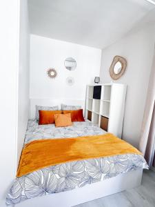 ein weißes Schlafzimmer mit einem großen Bett mit orangefarbenen Kissen in der Unterkunft Ô Confluent in Montereau-faut-Yonne