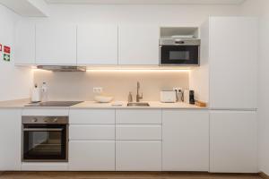 una cocina blanca con armarios y electrodomésticos blancos en Premium Apartment in the Center of Vilamoura - Cota10 by Centralgarve, en Vilamoura
