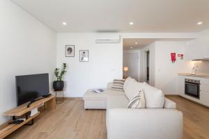 a living room with a white couch and a tv at Centralgarve - Premium Apartment in the Center of Vilamoura - Cota10 in Vilamoura