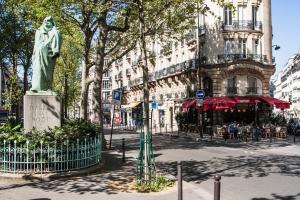 a statue in the middle of a city street at Hôtel Jardin Le Bréa in Paris