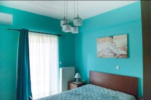 a blue bedroom with a bed and a window at Meropi Apartment in Preveza