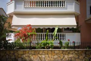 a building with a balcony with flowers and a fence at Meropi Apartment in Preveza