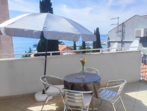 a table with chairs and an umbrella on a balcony at Apartment Sun in Baška Voda