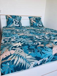 a bed with a blue and white blanket and pillows at Villa des pruniers in Saint-Denis