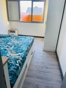 a bedroom with a bed with a blue blanket on it at Villa des pruniers in Saint-Denis