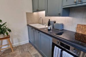 a kitchen with blue cabinets and a sink at The Old Barn Annexe, cosy stay near the city, beach, South Downs & Goodwood in Chichester
