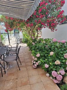 een patio met tafels en stoelen en roze bloemen bij Casa Blanca, Biograd na Moru in Biograd na Moru