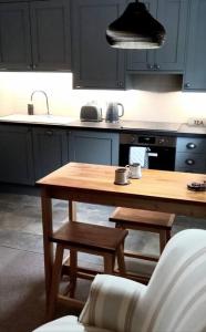 a kitchen with a wooden table and a kitchen with blue cabinets at The Old Barn Annexe, cosy stay near the city, beach, South Downs & Goodwood in Chichester