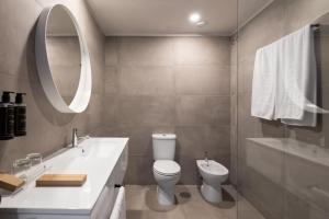 een badkamer met een toilet, een wastafel en een spiegel bij Exe Praia Golfe in Espinho