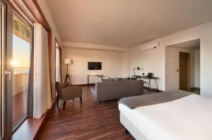een slaapkamer met een bed en een woonkamer met een bank bij Exe Praia Golfe in Espinho