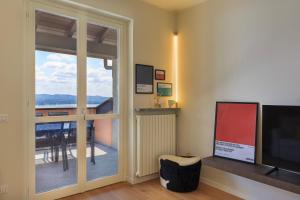 een woonkamer met een televisie en een glazen schuifdeur bij La Marmotta - Music Home in Belgirate