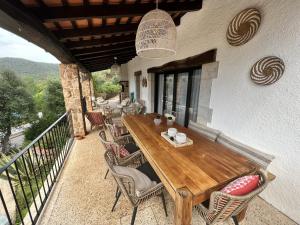 uma mesa de madeira e cadeiras numa varanda em Villa Torre Cal Sada em Vall-Llobrega