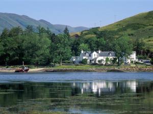 une maison sur la rive d'une masse d'eau dans l'établissement Kintail Lodge Hotel, à Kyle of Lochalsh