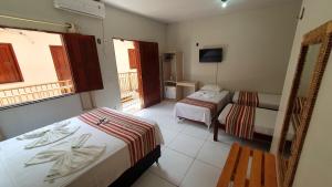 a hotel room with two beds and a television at Pousada Igarapé in Barreirinhas