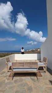 a person sitting on a wall with two benches at Under The Palm Tree Studios in Áno Meriá