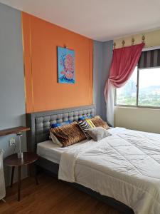 een slaapkamer met een groot bed met een oranje muur bij Ampang Hilir Lake View - Suite Unit and Rooms in Kuala Lumpur