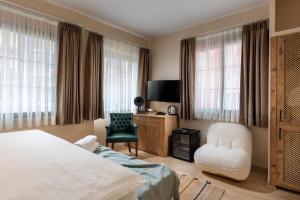 a bedroom with a bed and a chair and a television at Gran Via Alsancak in Konak