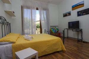 1 dormitorio con cama amarilla y TV en Casa Sophie Affittacamere, en Loreto
