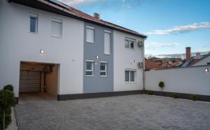 a white house with a garage and a driveway at Vár Apartman in Eger