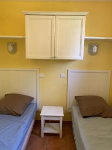 two beds in a room with a table and cabinets at Appartement Village P&V domaine du golf Pont Royal Provence avec PARC AQUATIQUE in Mallemort
