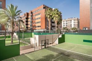 a tennis court in front of a building with palm trees at EnjoyGranada EMIR 3F - POOL, GYM & Free Parking in Granada