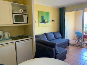 een keuken en een woonkamer met een bank en een magnetron bij Appartement à louer village P et V Domaine du Golf de Pont Royal en Provence in Mallemort