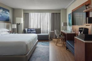 Tampa Marriott Water Street في تامبا: غرفة في الفندق بها سرير وأريكة ومكتب