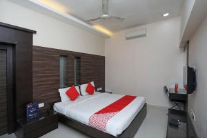 a bedroom with a bed with red pillows and a television at Hotel South Fern in Ballygunge