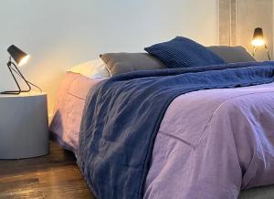 a bedroom with a bed with blue and purple sheets at Sur la Route de Beauval in Saint-Aignan
