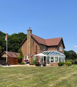 a large brick house with a greenhouse in the yard at Graceland Farm B&B in Brockenhurst