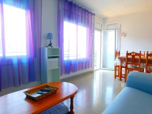 ロザスにあるGMID IMMO Apartment Mas Olivaの紫色のカーテンとテーブル付きのリビングルーム