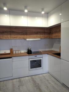 a kitchen with white appliances and wooden cabinets at Apartament w Morskim Stylu in Ustka