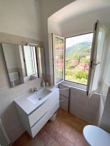 ein weißes Bad mit einem Waschbecken und einem Fenster in der Unterkunft Casa Angè - Lerici, Golfo dei Poeti in Lerici
