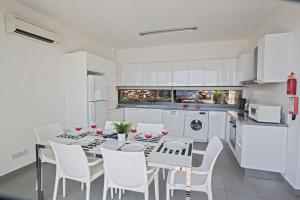 a white kitchen with a dining room table and white chairs at Esprit Villa 21 in Polis Chrysochous